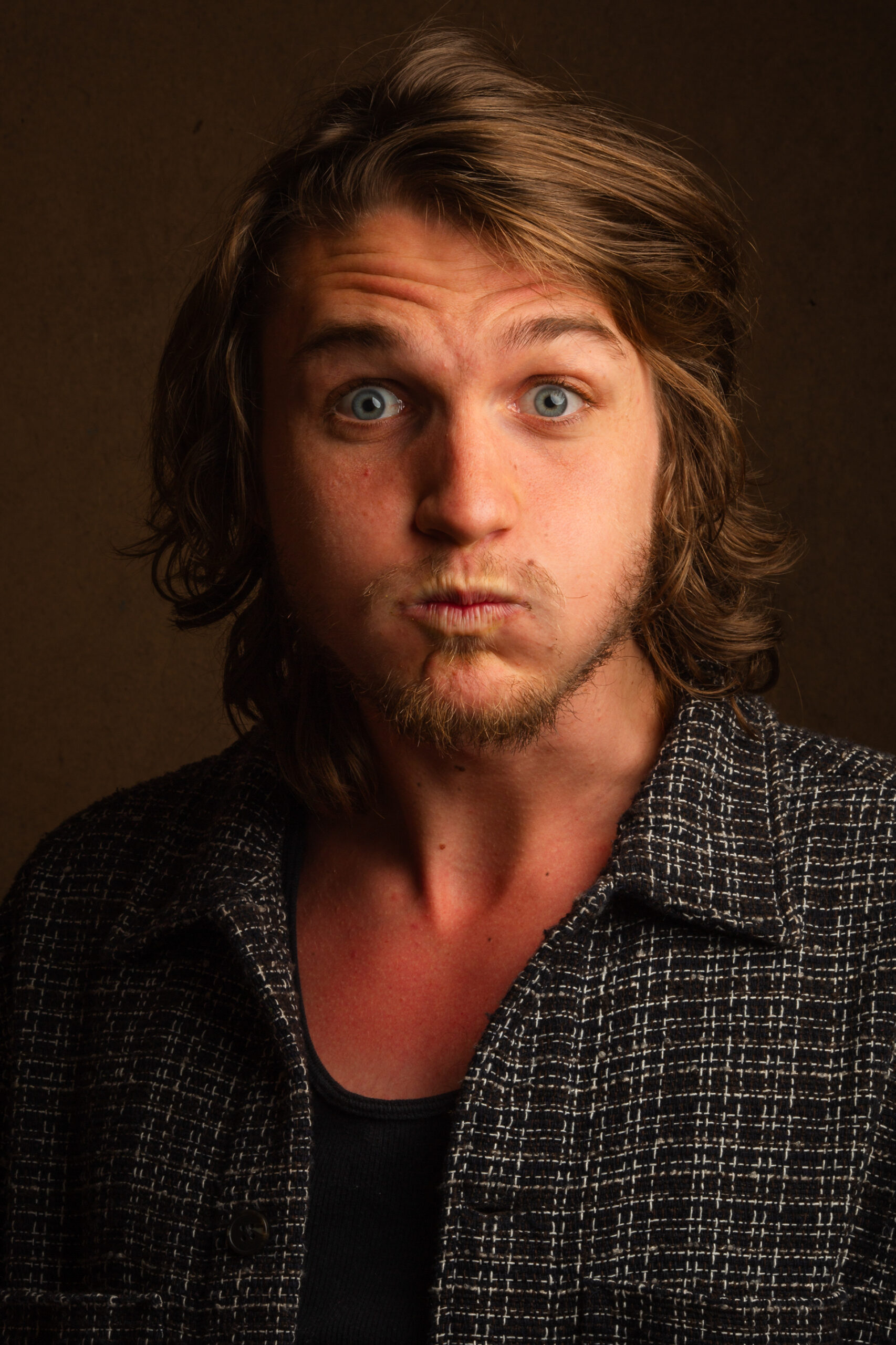 Retrato de hombre joven de pelo largo sobre fondo oscuro
