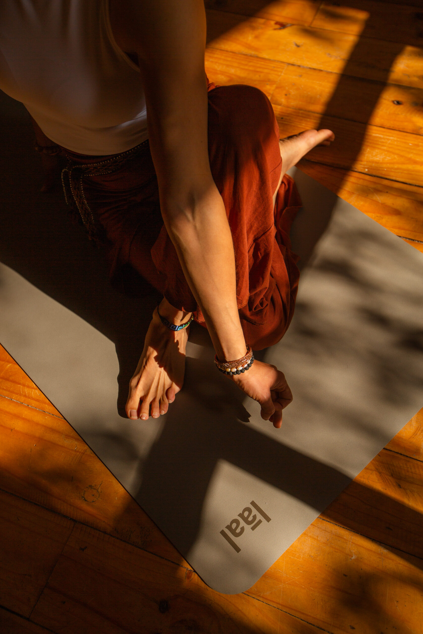 Pies de una practicante de yoga sobre un suelo de madera con luz de tarde