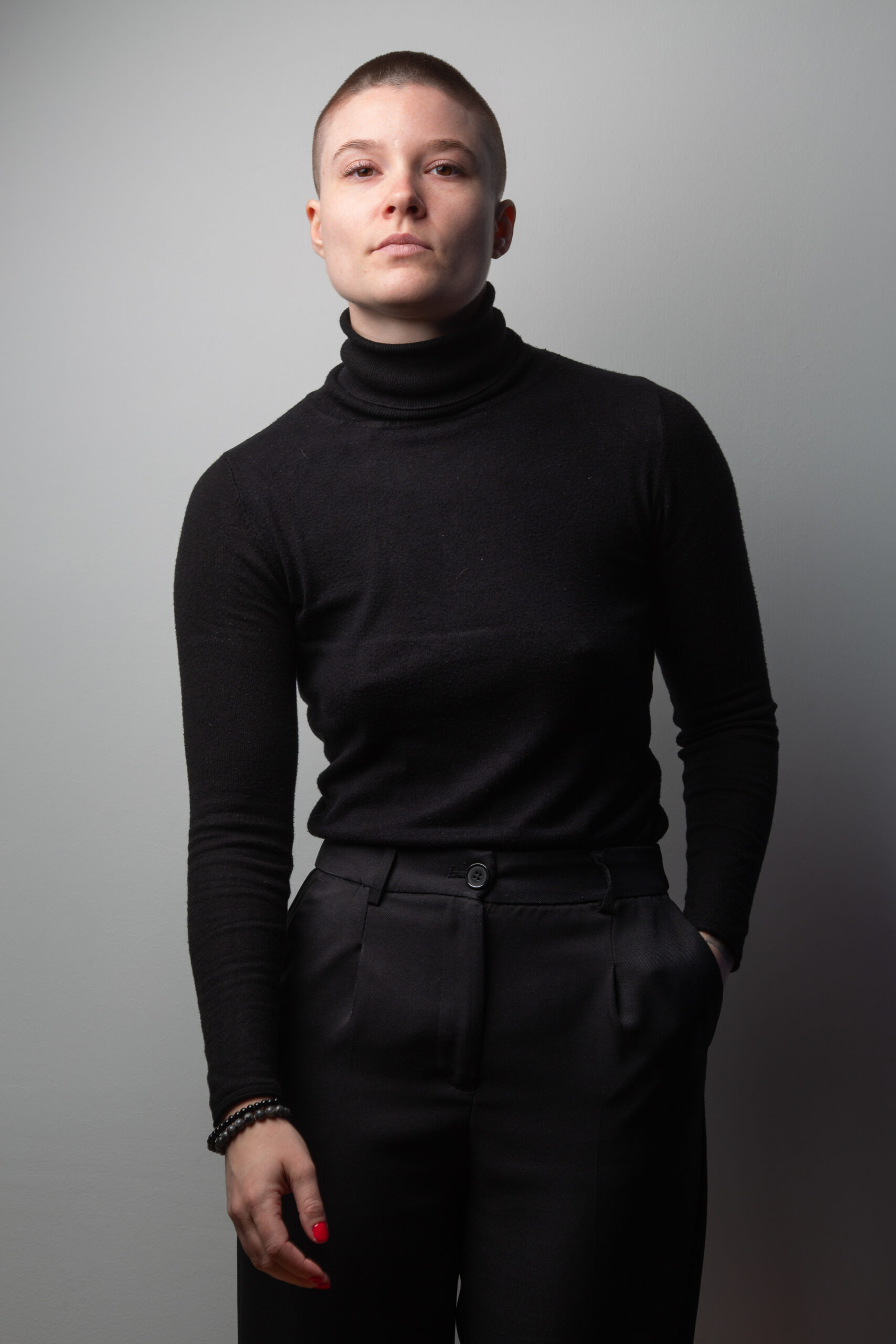 Retrato de una persona con jersey negro de cuello alto sobre fondo gris