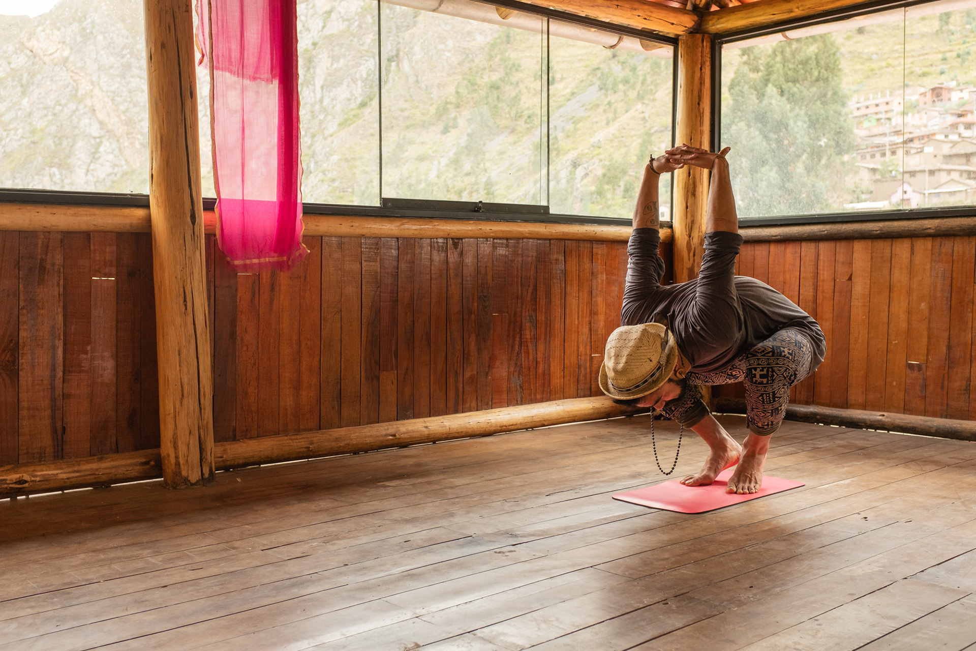 Practicante de yoga en postura invertida sobre una esterilla en una sala con ventanales